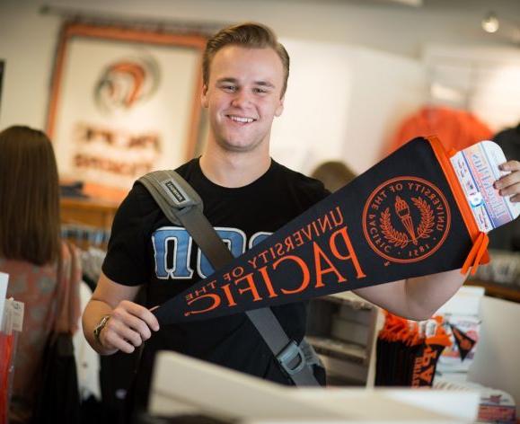 Smiling student holding Pacific pennant